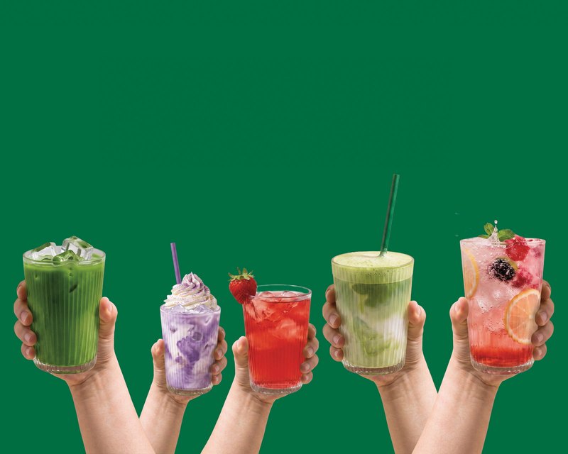 Five hands raising Allreasons drinks: matcha latte, ube latte, refresher, matcha and berry drinks