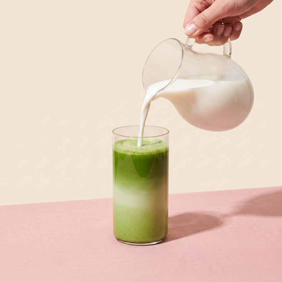 Matcha latte being poured into a glass, milk layering over green matcha