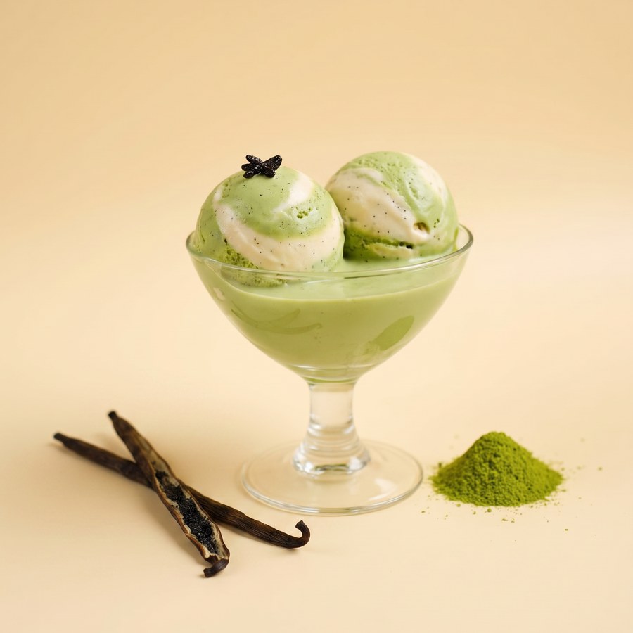 Matcha gelato with a vanilla ribbon in a glass coupe, beside vanilla pods