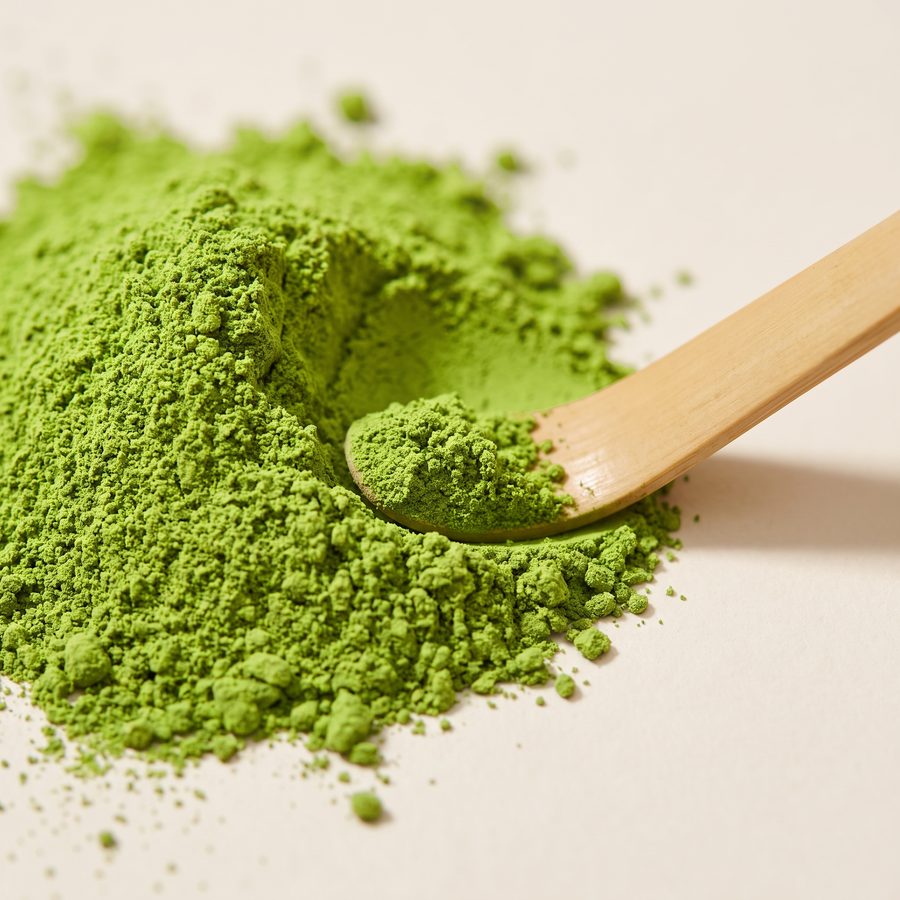 Close-up of fine vivid green Organic Ceremonial Matcha powder with a bamboo scoop