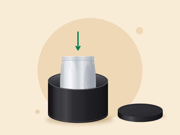 A sealed foil bag going into an open black tin, with the lid beside it